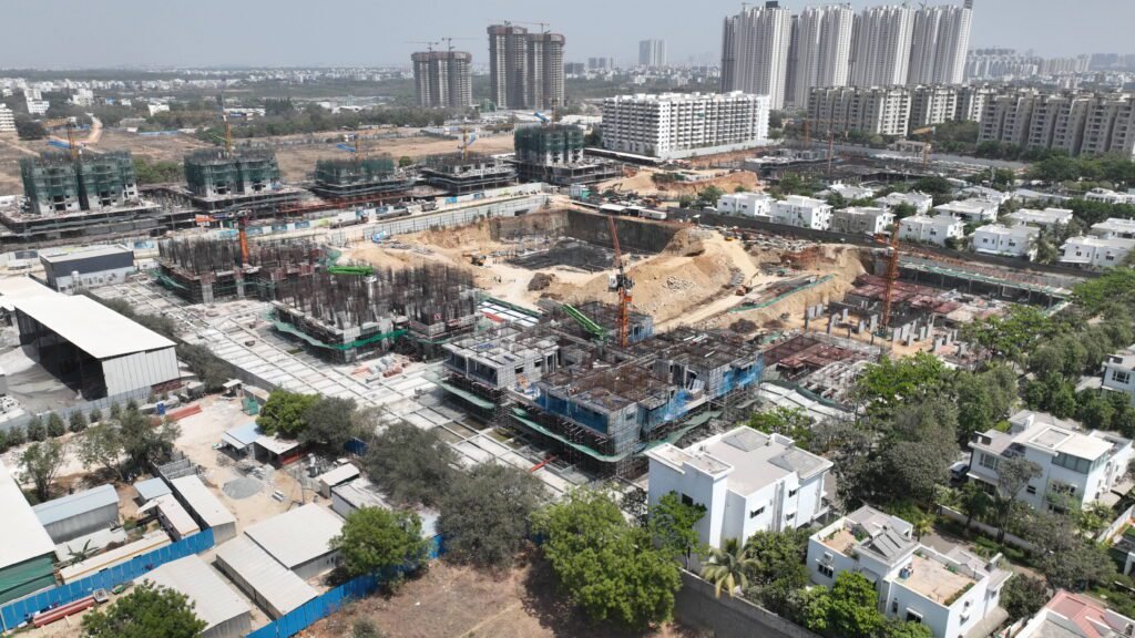 “Drone shot of Gamya by Supadha development under construction, surrounded by residential buildings and greenery”